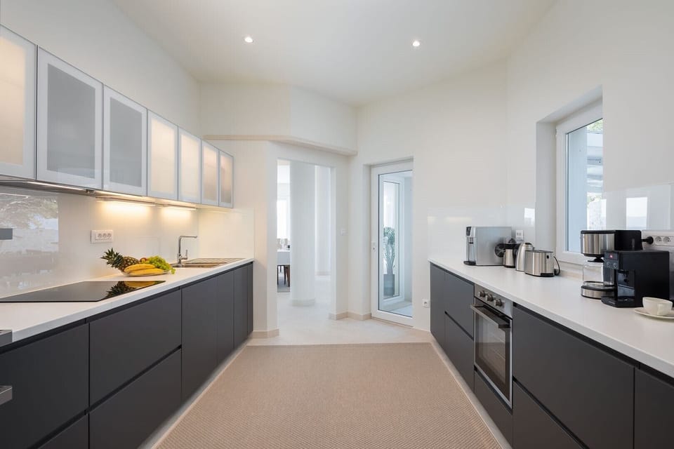 Fully equipped kitchen with contemporary black cabinets, coffee machine, ice maker, toaster and water kettle on the ground floor of the private dalmatian villa Sutivan Infinity
