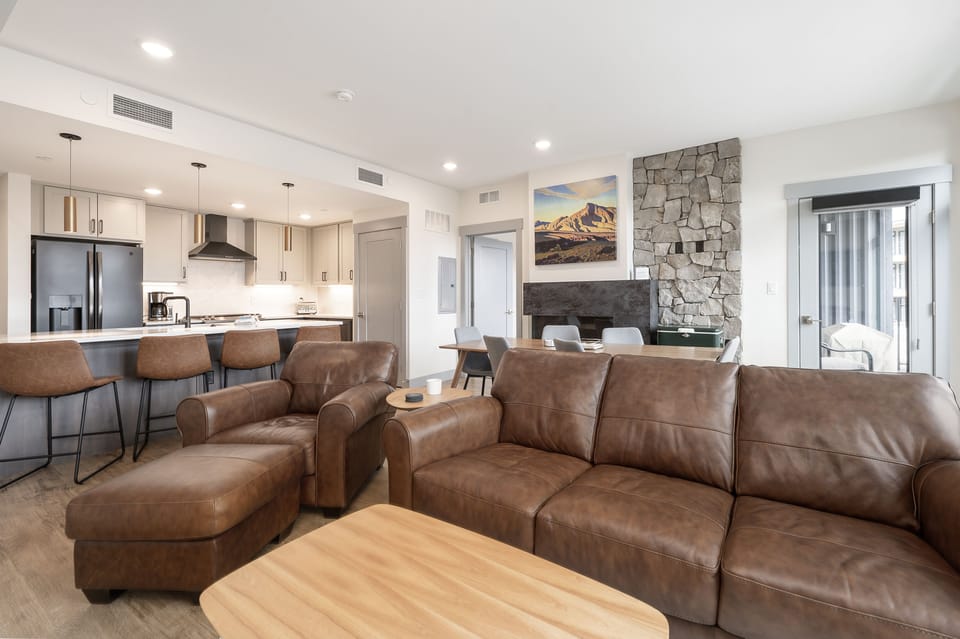 - Spacious living room with leather sofa seating   - Stone fireplace creates warm mountain atmosphere   - Open plan connects to kitchen and dining space