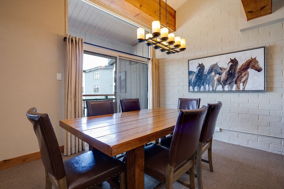 Gather around this rustic dining table for memorable meals with your group, warmed by the elegant chandelier and stunning horse artwork.