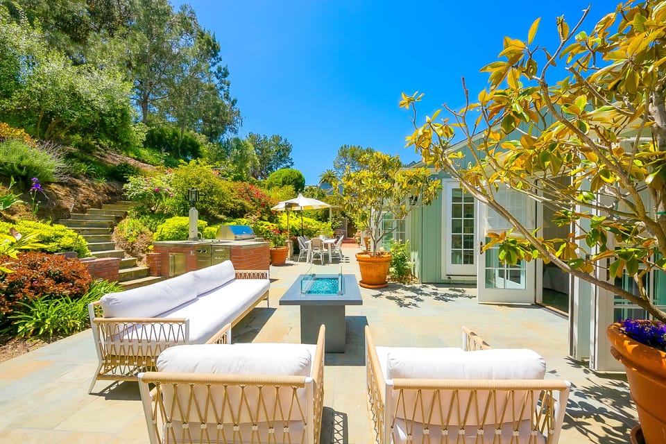 Step out from the primary suite to this serene backyard retreat with lush greenery and stylish lounge seating.