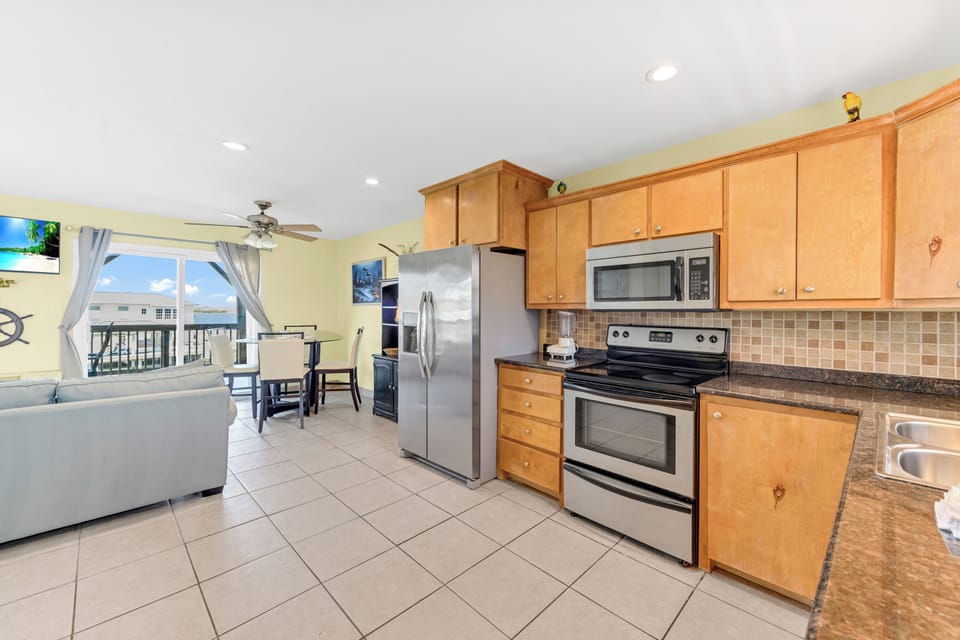 Your open-plan kitchen flows seamlessly into the living area, featuring granite counters, stainless appliances, and ocean views from every window.