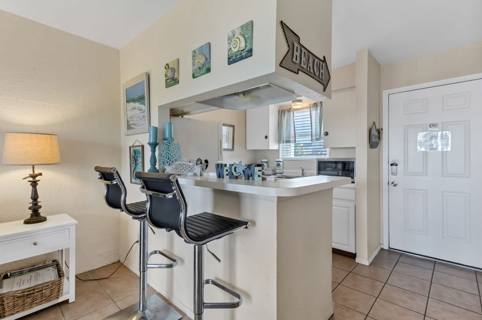Step into your bright, coastal-themed kitchen with modern bar seating where you can sip morning coffee or chat while preparing meals.
