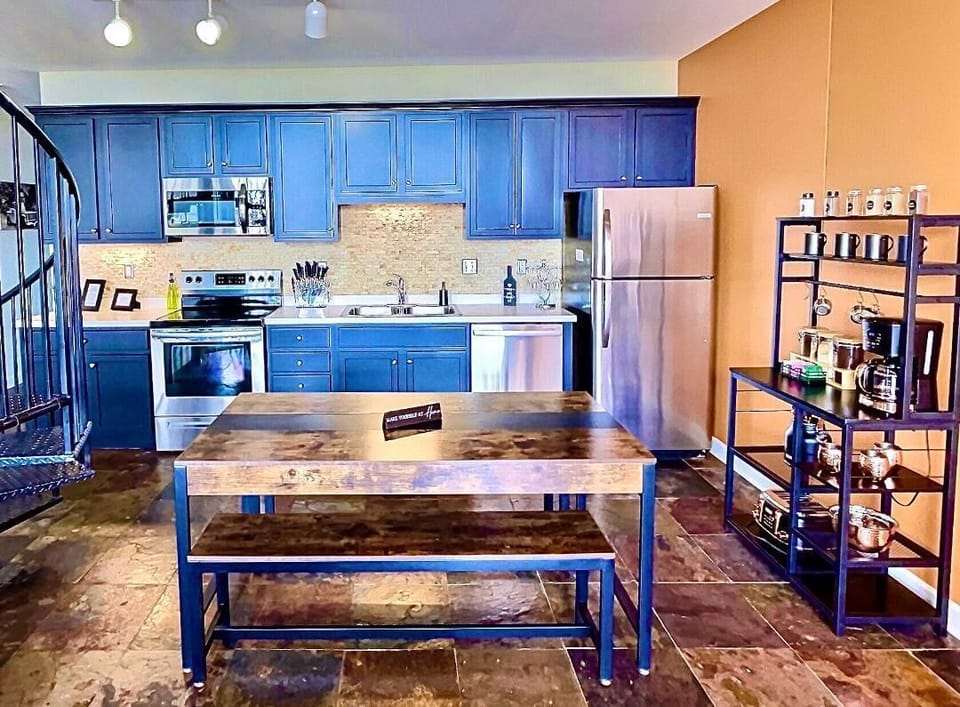 Fully Equipped Modern Kitchen
Cook with ease in this well-stocked kitchen featuring navy cabinetry, stainless steel appliances, and a warm, inviting dining area. Ideal for casual breakfasts or dinner gatherings.