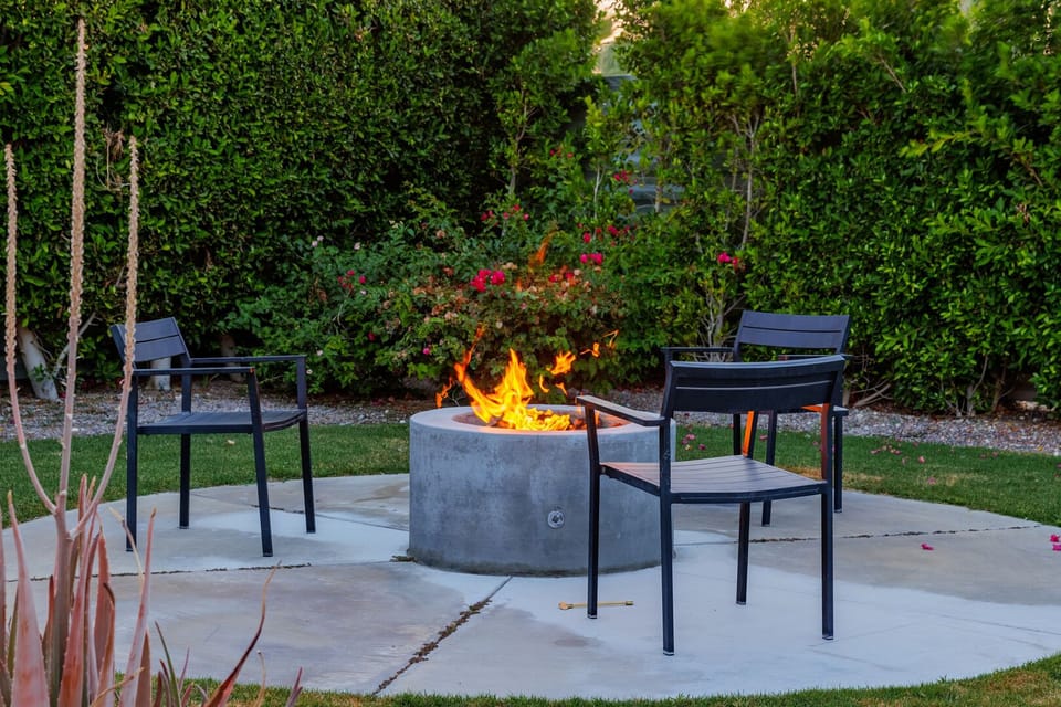 Backyard offers a firepit with seating for three near the pool area. 
