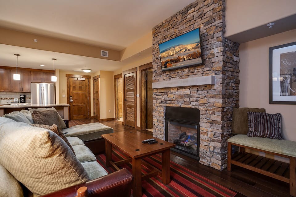 Unwind by your cozy stone fireplace with plush seating and mountain views on the wall-mounted TV.