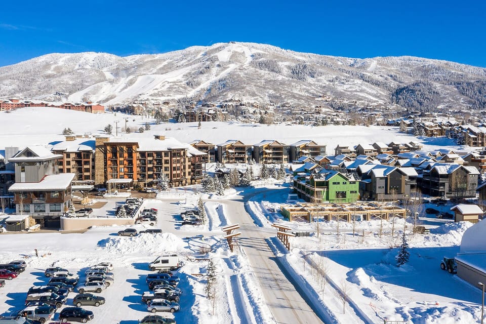 Snow-covered mountain resort community nestled beneath pristine alpine peaks on a brilliant winter day.