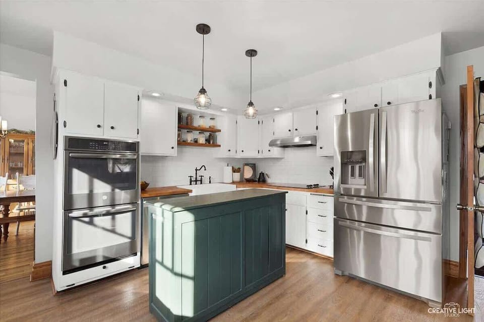 (KITCHEN) Enjoy culinary bliss in this fully equipped kitchen with a farmhouse sink, glass top stove, double ovens, and a roomy French door fridge with filtered water and an ice maker.