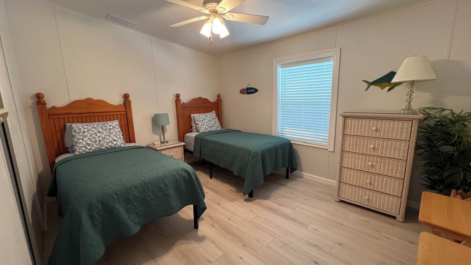 Guest bedroom with twin beds, nightstand, dresser and closet.