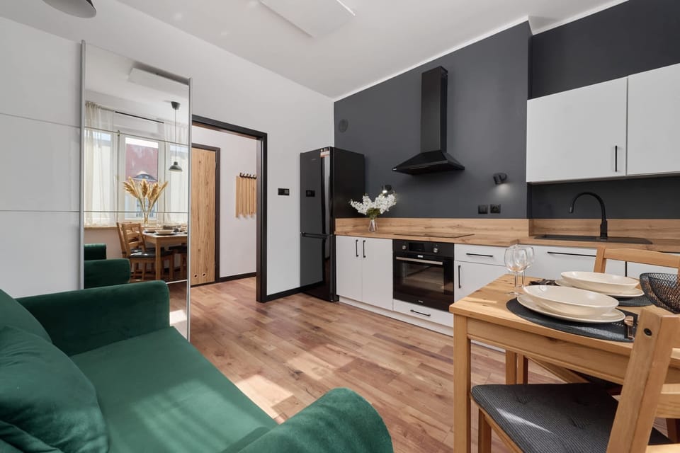 A spacious open-plan living room and dining area with stylish furnishings, including a green armchair and a modern wooden table. 