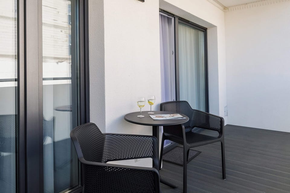 A private balcony featuring a small table and chairs, overlooking a peaceful garden.