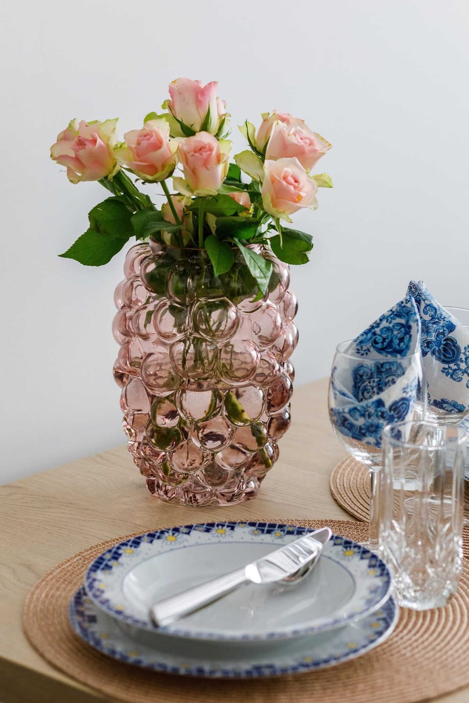 A close-up of a dining table set with decorative plates, glasses, and a vase with flowers.