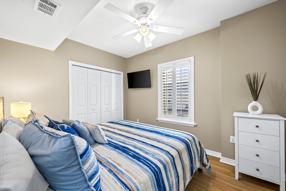 2nd bedroom with king bed, chest of drawers, wall mounted tv and closet