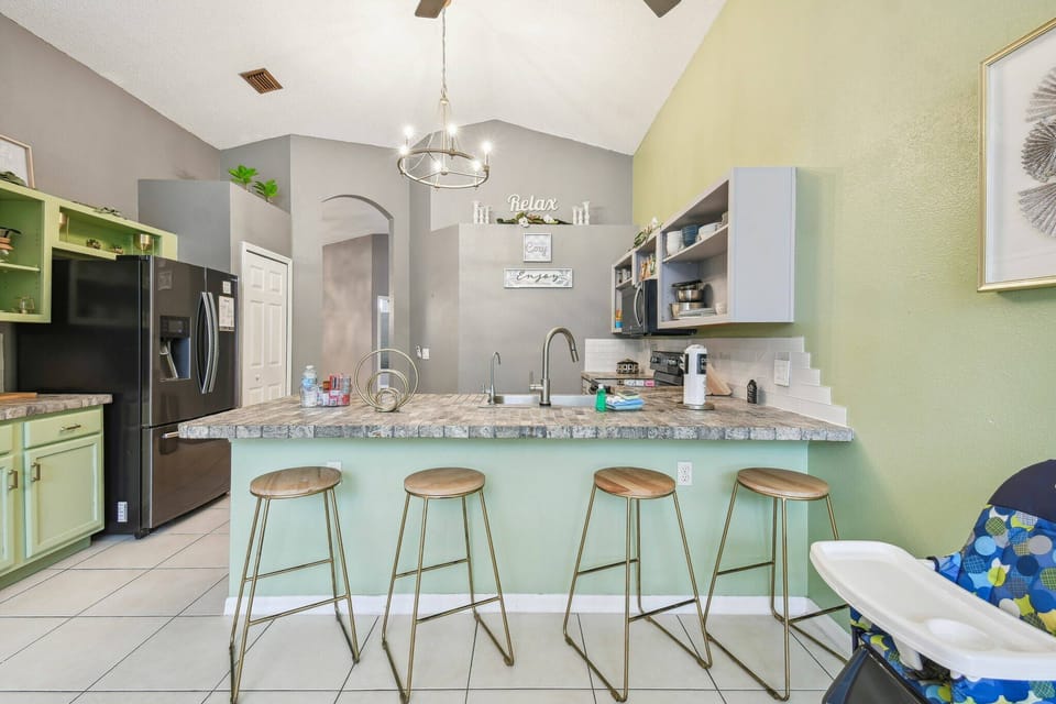 Welcome to a vibrant kitchen with soft green walls and sleek granite countertops. Enjoy casual meals at the stylish bar with chic, backless stools, and take advantage of modern appliances for ultimate convenience.