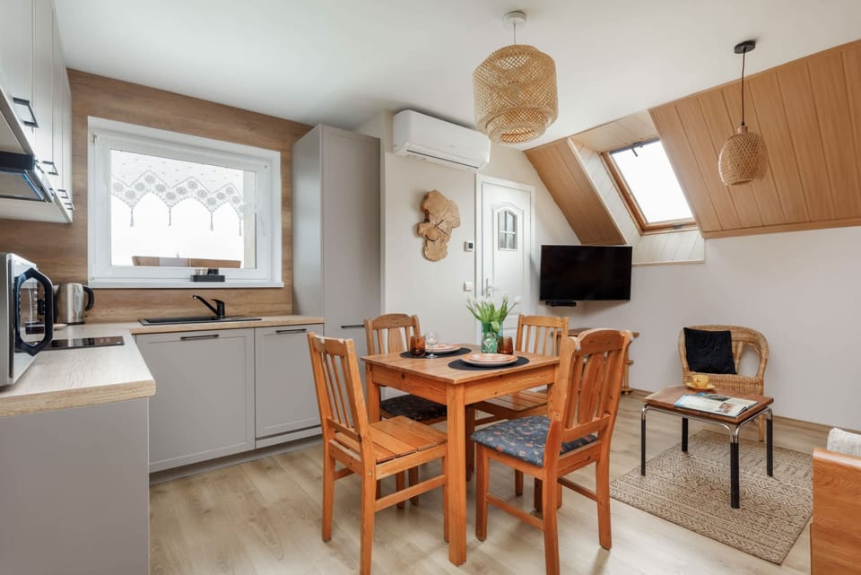 A wide-angle view of the dining and living area, showing a wooden dining table, chairs, and a comfortable sofa.
