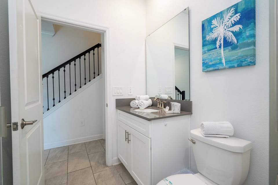 Bright, modern bath with a large mirror, quartz countertop, and plush towels-conveniently located near the stairs for easy access.
