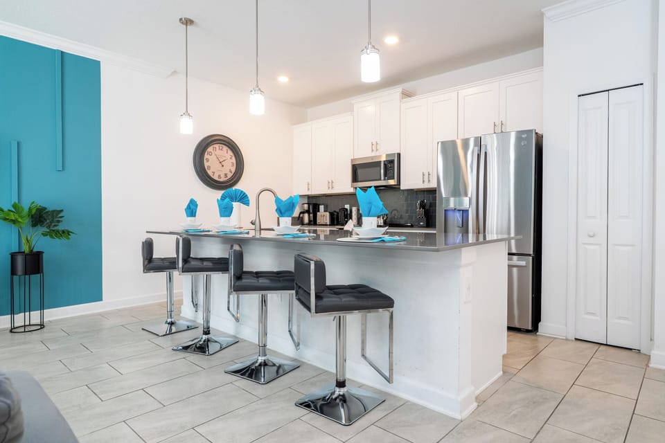 Chef-ready kitchen with stainless appliances, white shaker cabinets, pendant lights, and a spacious island with ample bar seating.
