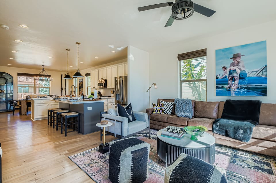 This sun-drenched open-concept space features a gourmet kitchen with a large island, a cozy living area with a leather sofa, and stylish accents. Perfect for seamless, modern mountain living.
