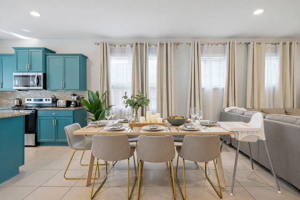 Bright open kitchen-diner with teal cabinets, seats six plus high chair.