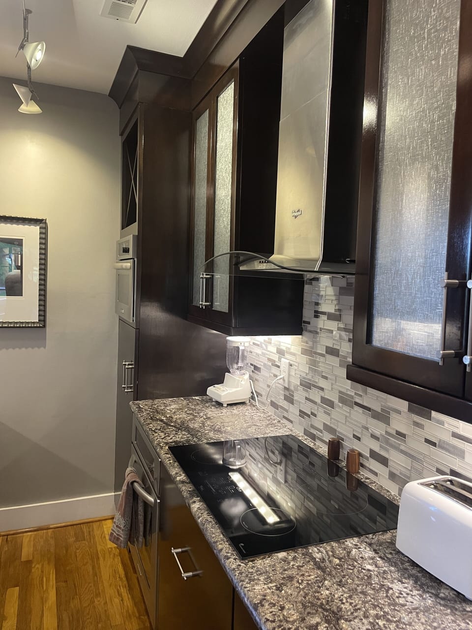 Kitchen with induction cooktop, built in refrigerator, oven and microwave.