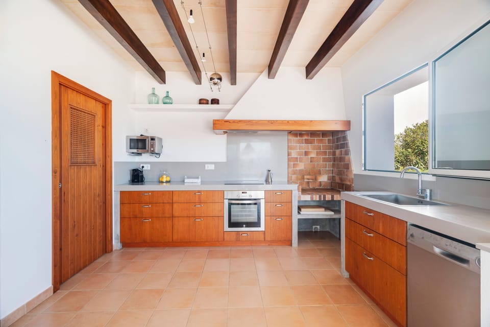 Vista total de cocina en L, equipada con horno, placa, lavavajillas y microondas