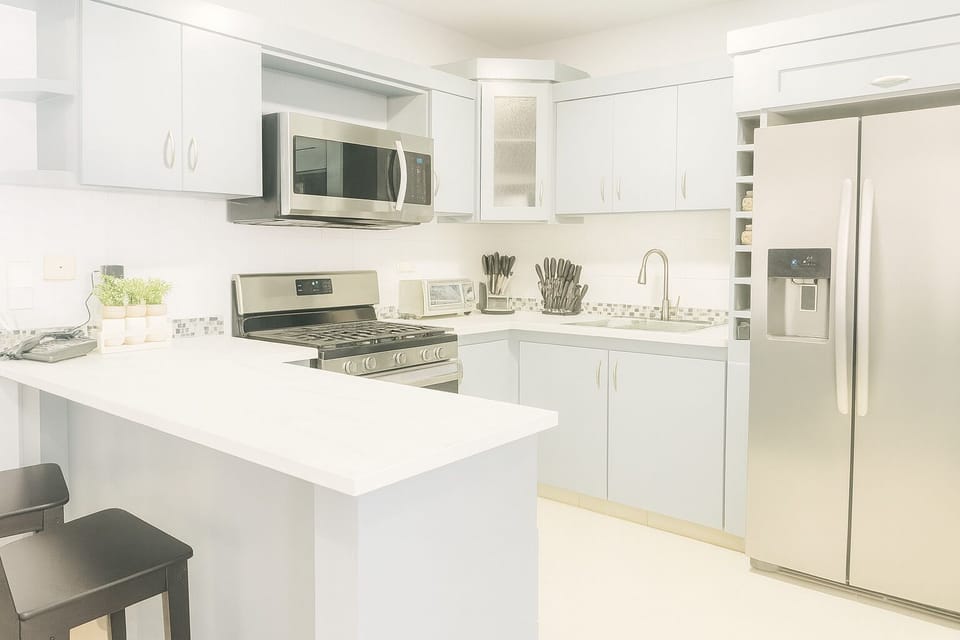 Discover a functional kitchen featuring a two-seater peninsula, perfect for quick bites or intimate conversations. The full-size refrigerator ensures ample storage for your culinary delights, adding convenience to your cooking experience. 
