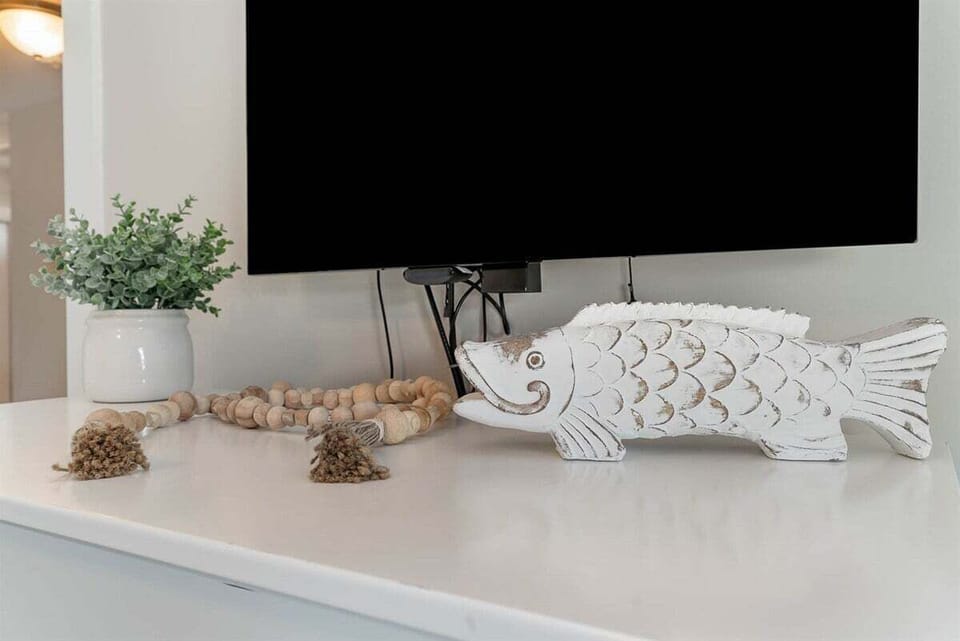 A detailed shot of the home's decor, featuring a carved white fish sculpture and natural bead accents on a white console.