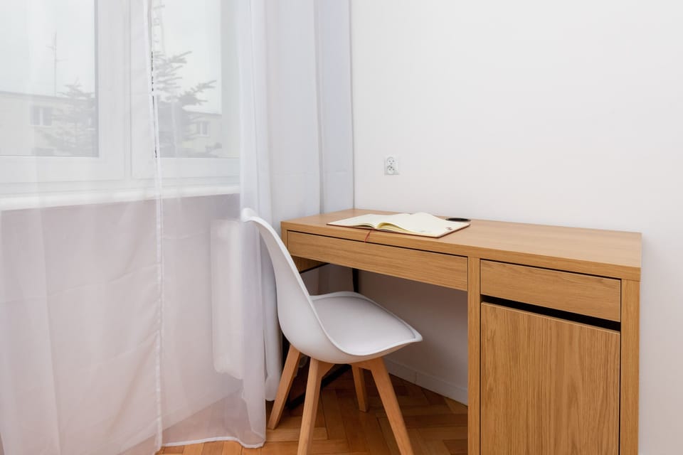 A small desk by the window with wooden details and a minimalist design, ideal for work.