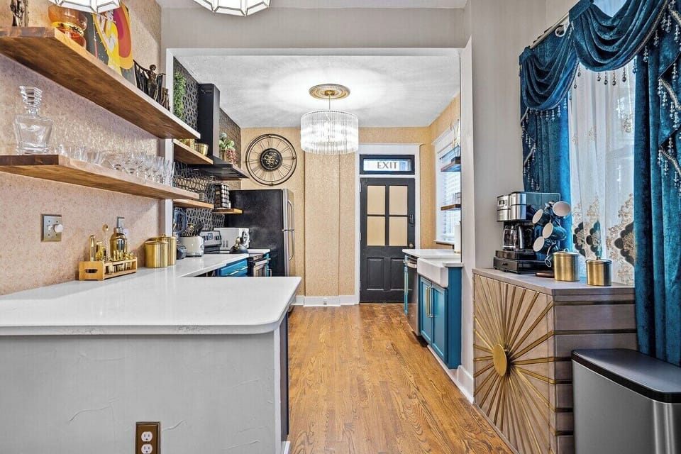 Cook in style in The Gatsby’s fully equipped lower-level kitchen, featuring bold blue cabinetry, open shelving, quartz counters, and modern appliances—perfect for extended stays in Midtown Kansas City.
