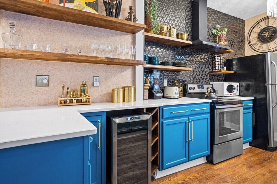 The Gatsby’s lower-level kitchen blends functionality and flair with rich blue cabinets, custom shelving, and a wine fridge—your perfect home base between Downtown, Westport, and the KC Streetcar.