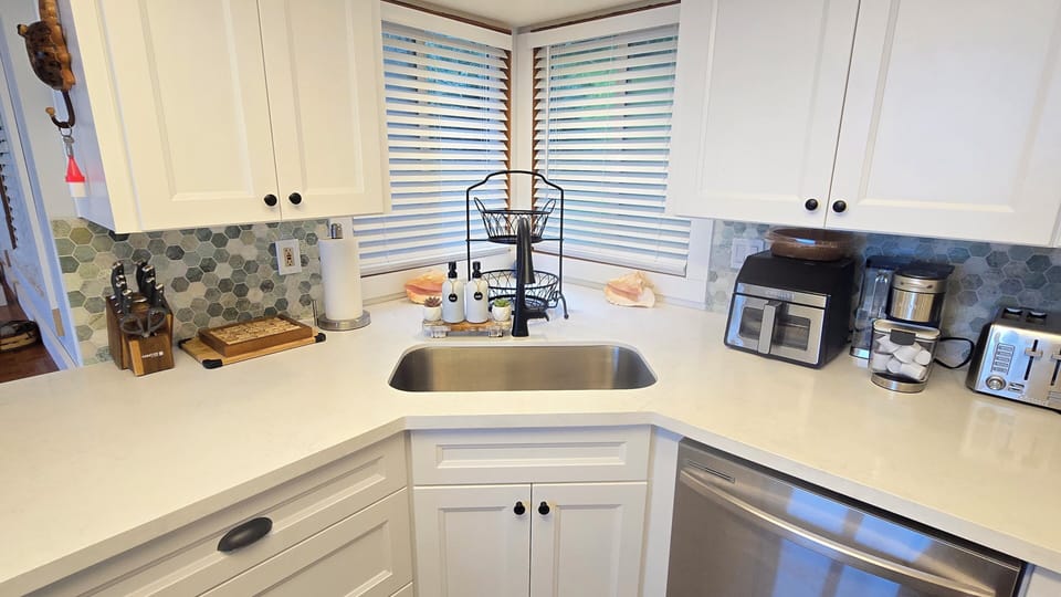 Large kitchen sink with deep counters and gas stove. Many appliances for use.