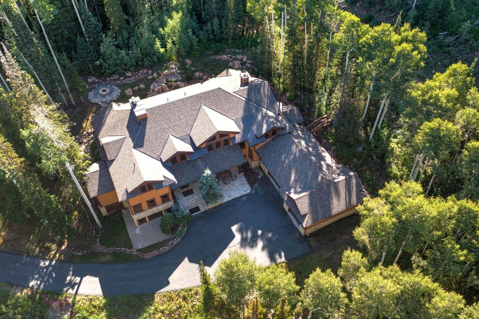 This expansive mountain retreat sits nestled among towering aspen and evergreen trees, offering peaceful seclusion and a scenic forested setting. The property features multi-level architecture with ample parking and outdoor spaces.