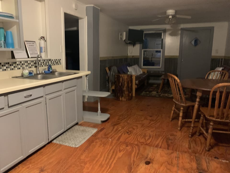 full kitchen opens to living room with two futons and covered balcony porch
