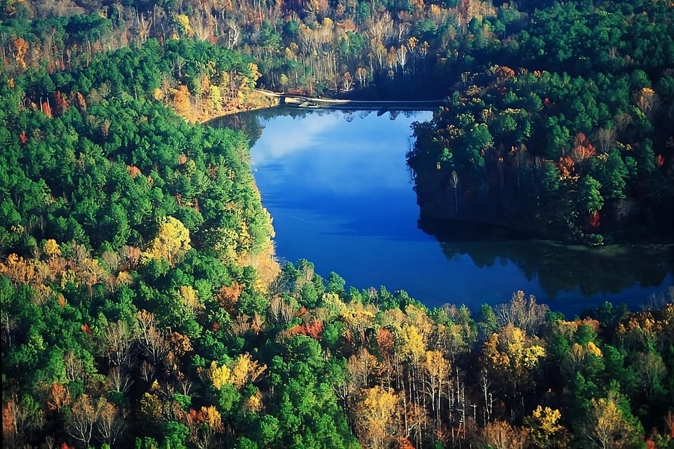 Explore a sweeping lake panorama surrounded by colorful forested hills.
