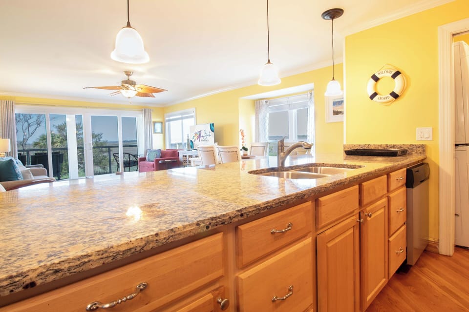 Imagine yourself preparing meals in this bright, open kitchen with its gleaming granite countertops and abundant natural light—then stepping out to savor ocean breezes through the expansive glass doors.
