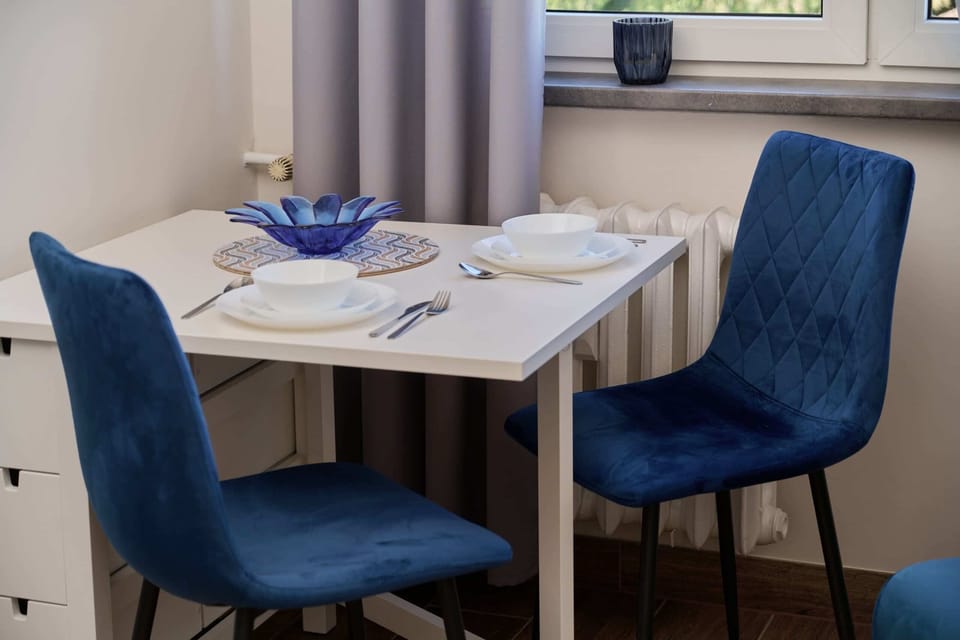 A dining table set for two, featuring soft blue chairs and a cozy atmosphere by the window.
