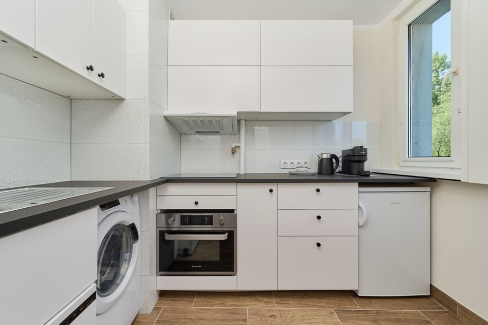 A compact yet functional kitchen, fully equipped with white cabinetry, an oven, and ample counter space.
