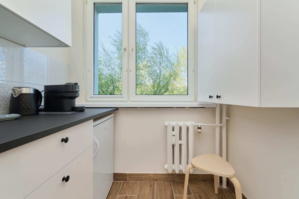 A view of the kitchen corner, with bright windows bringing in natural light and a view of the surrounding greenery.
