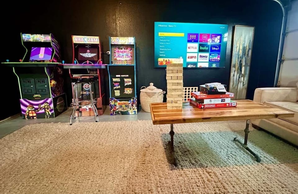 This side of our game room features a variety of arcade games, board games, and a TV perfect for a movie marathon. With a comfortable couch and a stylish wood table, it's the ultimate space for fun and relaxation.