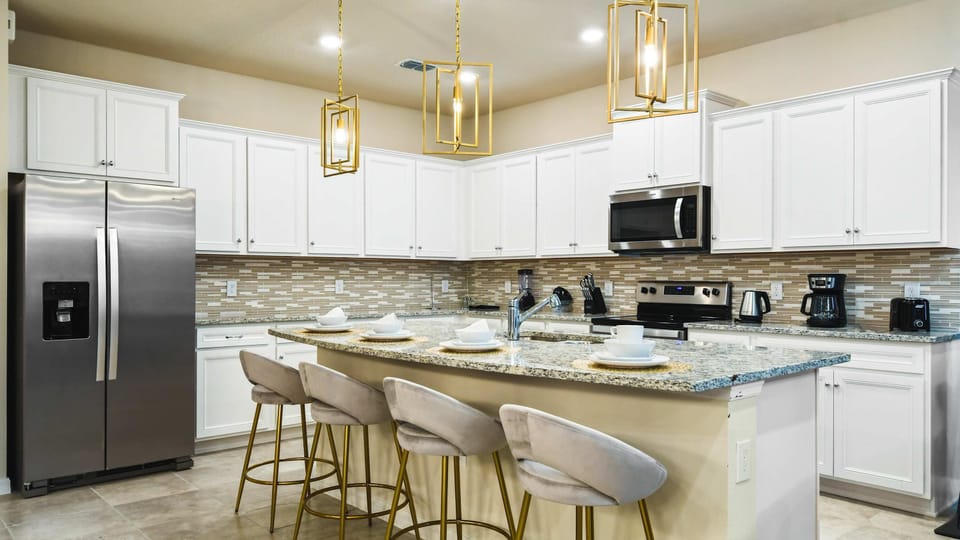 Modern kitchen with granite countertops, stainless steel appliances, and bar seating.
