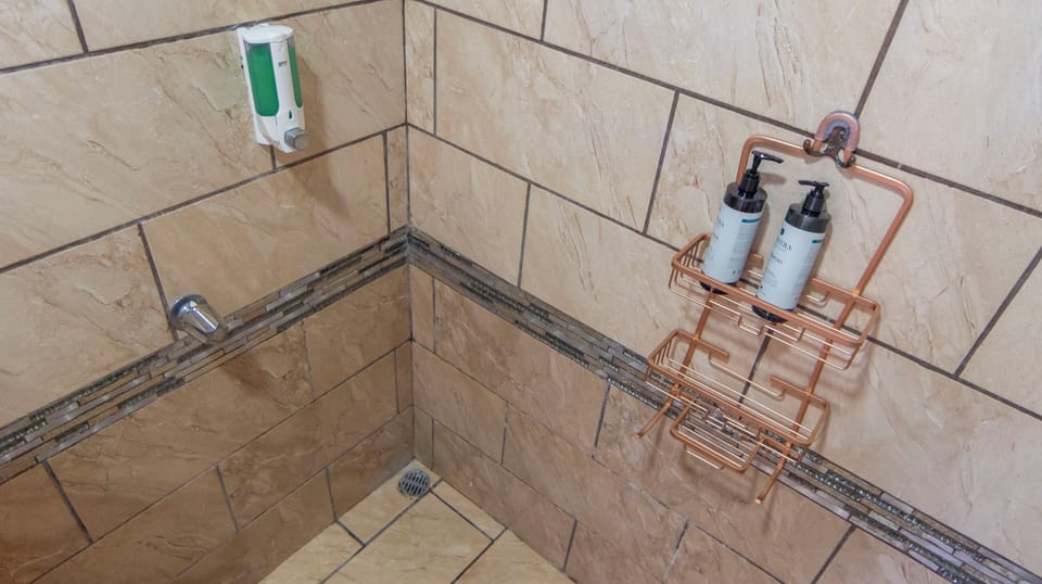 Bathroom 1: tiled shower with a small high window.