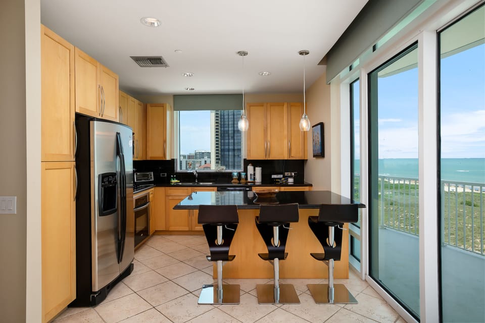Fully equipped kitchen with stainless steel appliances and breakfast bar seating with Gulf views.