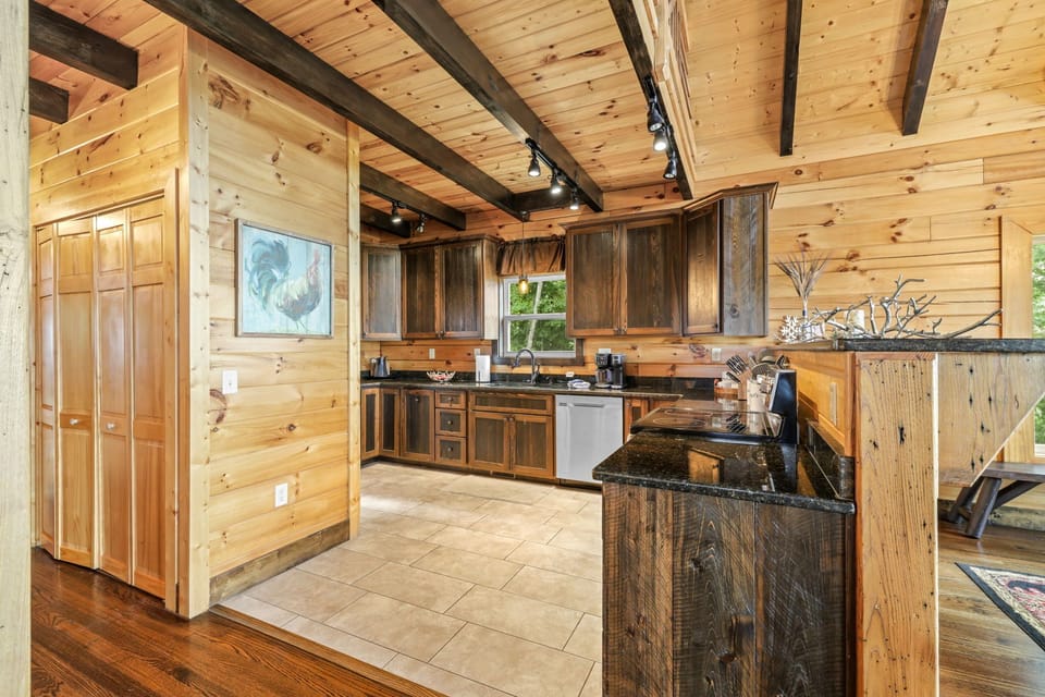 Fully equipped kitchen with dark wood cabinetry, granite countertops, stainless steel appliances, and an open layout connecting to the living space. Designed for convenient meal preparation during your Bryson City mountain getaway.
