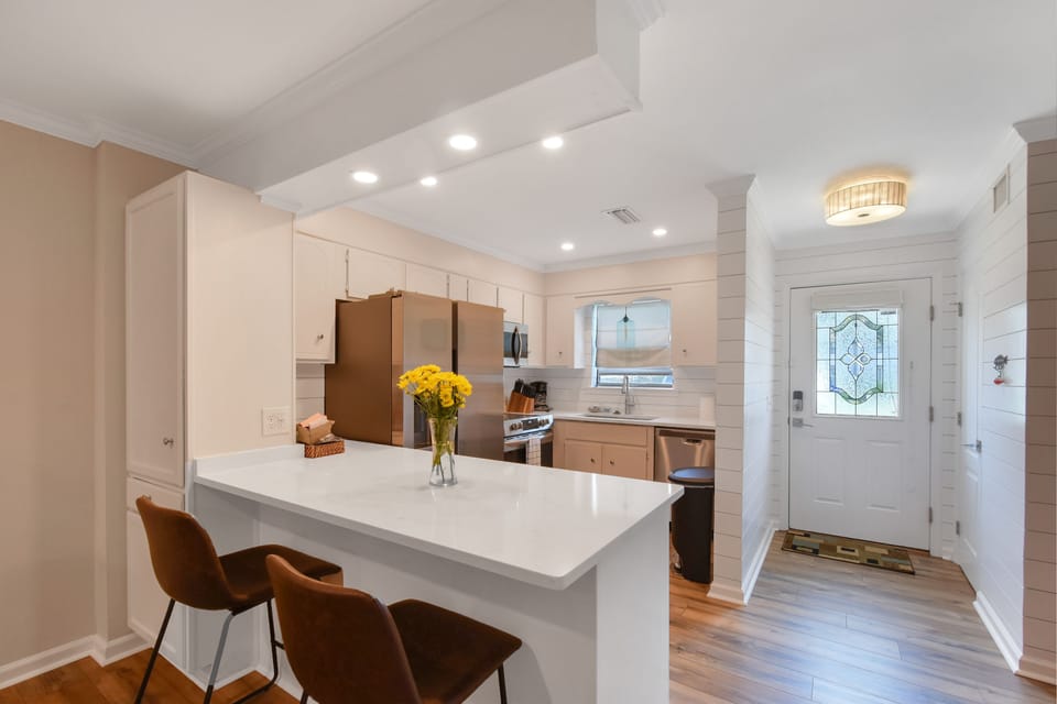 Remodeled Kitchen with Island Seating - The updated kitchen at Courtyard Villas E-5 features quartz counters, modern appliances, and island seating. Shiplap walls and recessed lighting bring a fresh, beachy vibe to this St. Simons vacation rental.