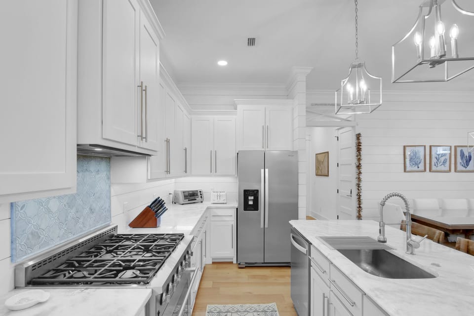 Kitchen Overview – Gas Range, Island Sink & Open Dining Flow - The full kitchen view—gas range, marble island with sink, and open access to the dining room. Whether you're making coffee or cocktails, it's a space built for connection.