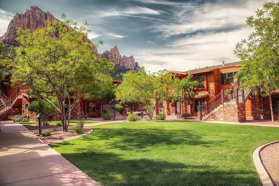 Stroll quiet pathways through lush lawns beneath towering red rocks.