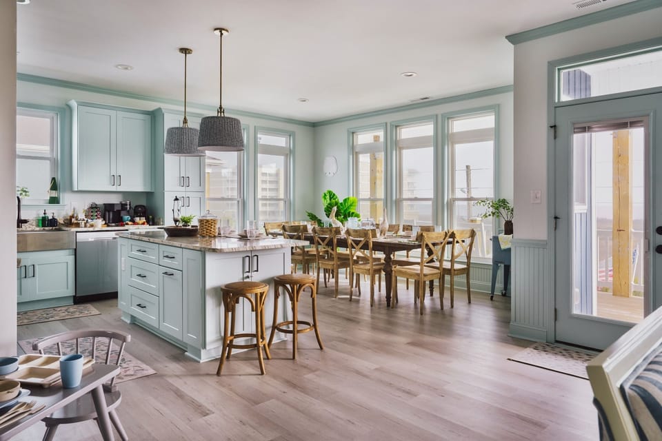 Open kitchen layout, chic dining table, and a stylish bar with stools on the upper level
