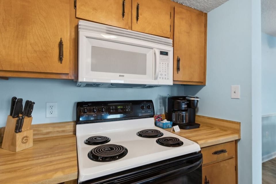 Kitchen cooking station with electric range, microwave, and coffee setup.
