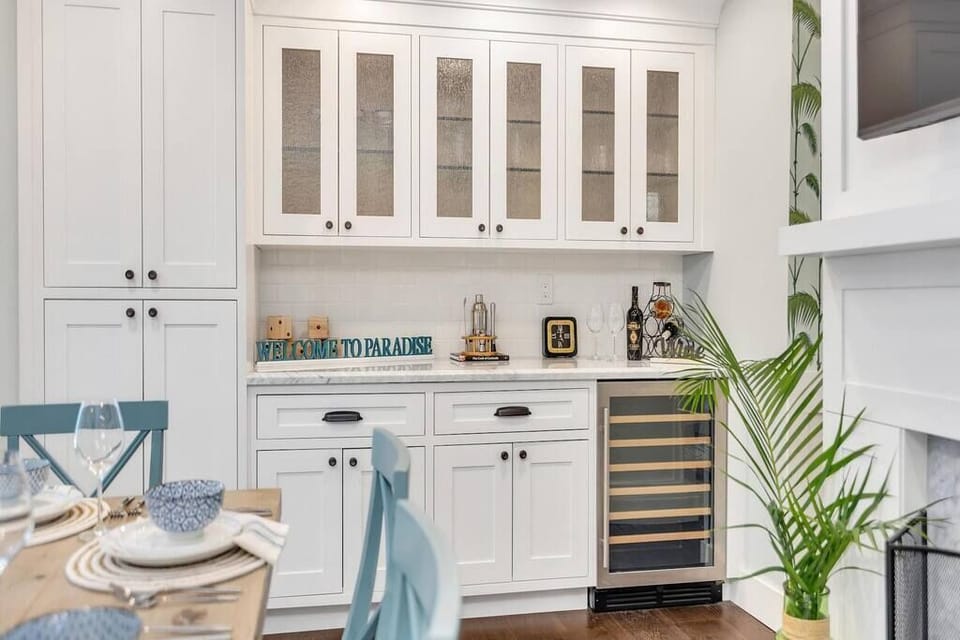 Modern white cabinetry with glass doors and a built-in wine cooler in the dining area