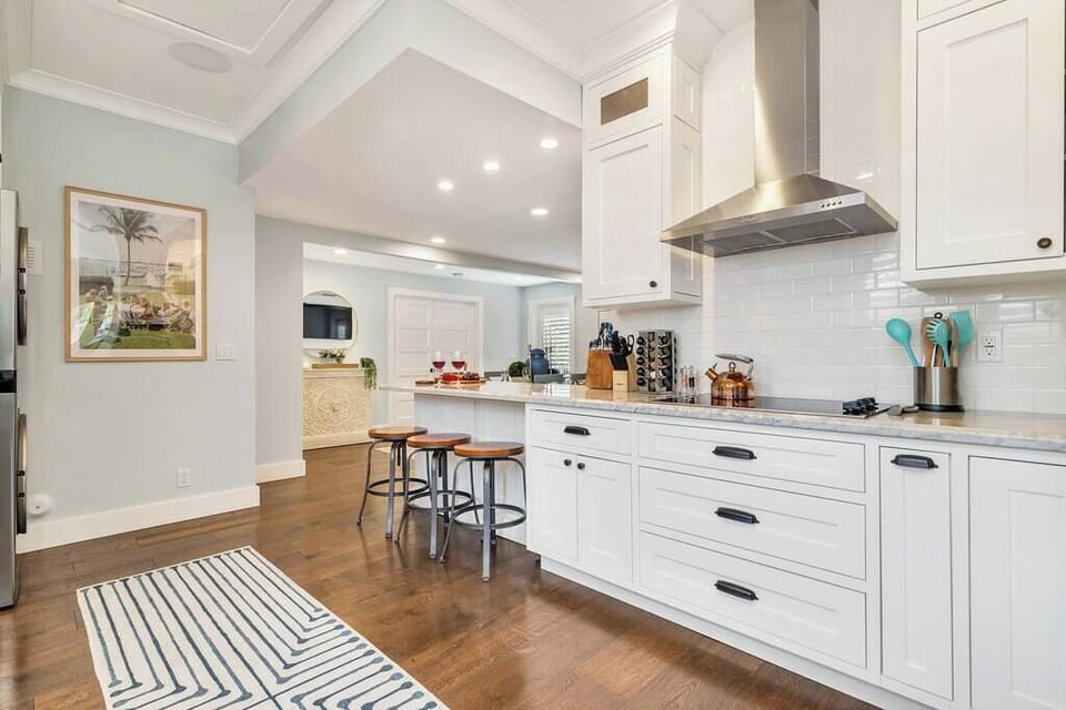 Modern kitchen with white cabinetry and a breakfast bar with stools