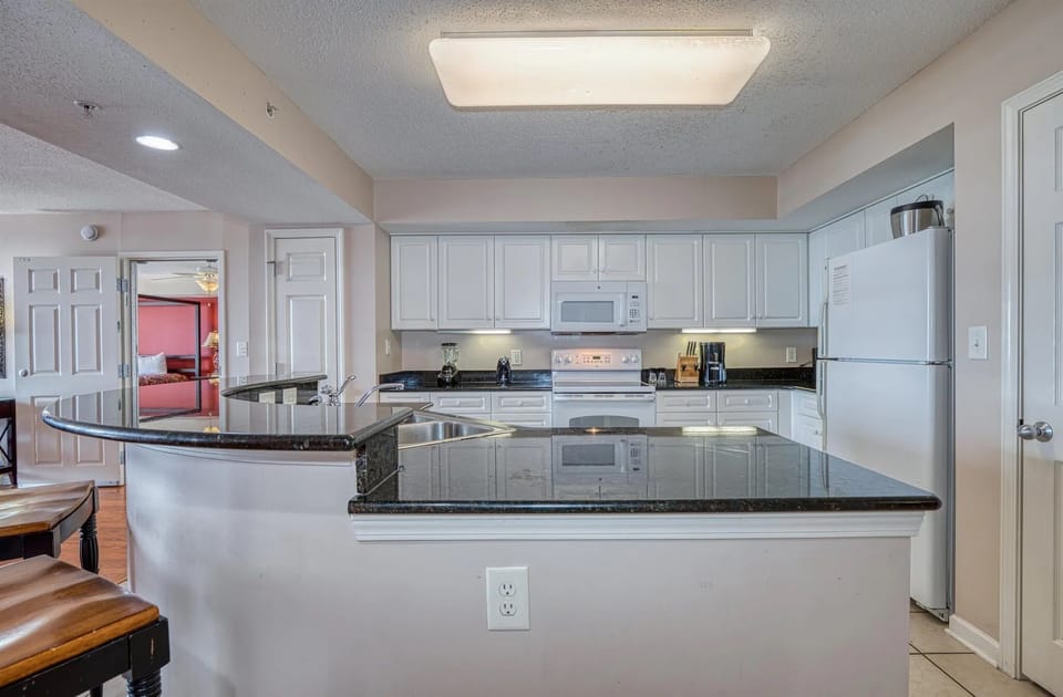 Sleek breakfast bar with high stools and tile flooring throughout